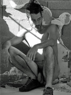 Männerakt-Fotografie eines hockenden jungen Mannes